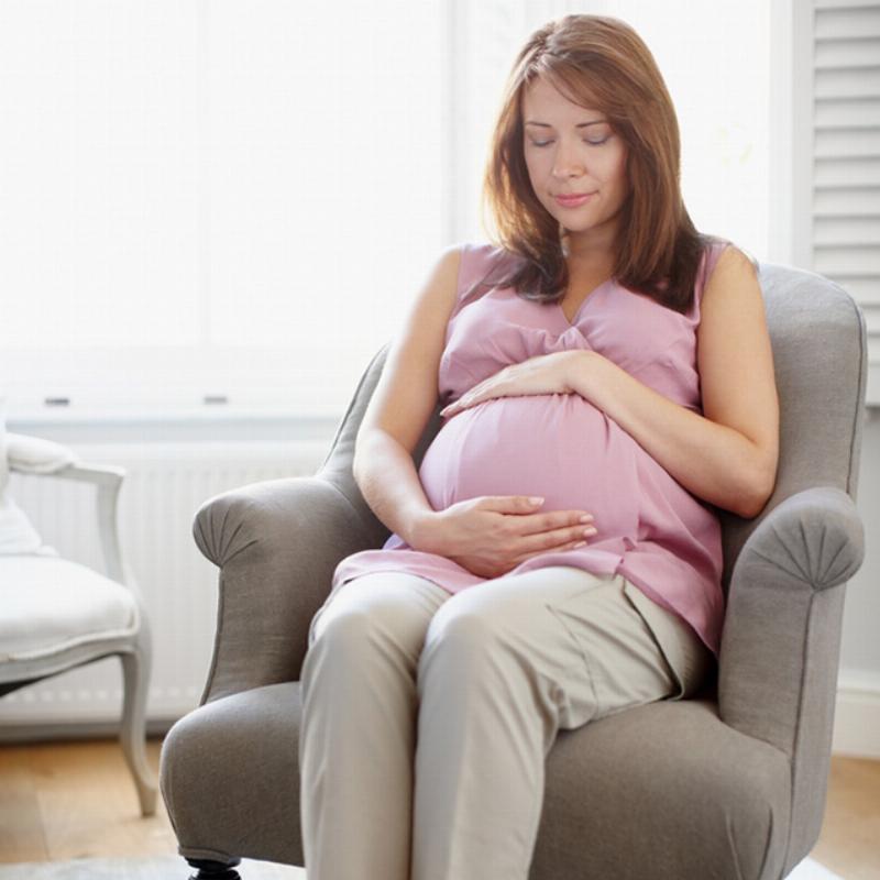 Bà bầu nằm thư giãn trên ghế sô pha, nghe nhạc nhẹ nhàng qua tai nghe